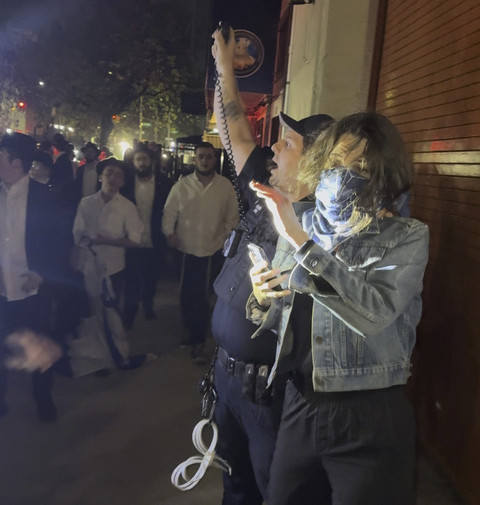 Gambar yang diambil dari video ini menunjukkan seorang wanita dan seorang petugas polisi saat mereka dikejar oleh kerumunan pria di bagian Crown Heights, Brooklyn, N.Y., pada Kamis (24/4/2025). Foto: AP Photo