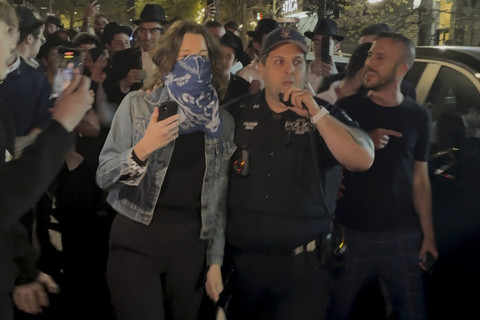 Gambar yang diambil dari video ini menunjukkan seorang wanita dan seorang petugas polisi saat mereka dikejar oleh gerombolan pria Yahudi Ortodoks di bagian Crown Heights di Brooklyn, N.Y., pada Kamis (24/4/2025). Foto: AP Photo