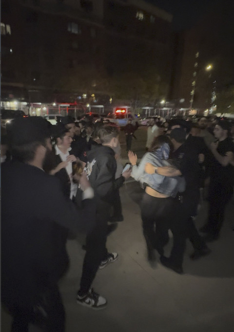 Gambar yang diambil dari video ini menunjukkan seorang wanita dan seorang petugas polisi saat mereka dikejar oleh kerumunan pria di bagian Crown Heights, Brooklyn, N.Y., pada Kamis (24/4/2025). Foto: AP Photo
