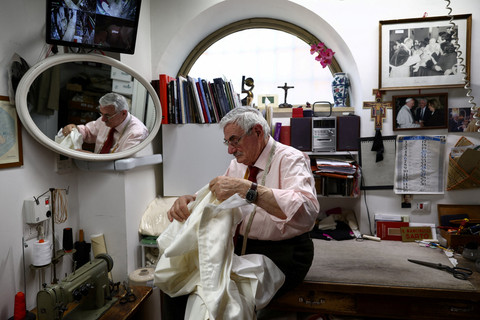 Penjahit jubah pendeta Raniero Mancinelli sedang mengerjakan jubah kepausan putih di toko perlengkapan liturgi miliknya di dekat Vatikan, di Roma, Italia, Selasa (29/4/2025). Foto: Guglielmo Mangiapane/REUTERS