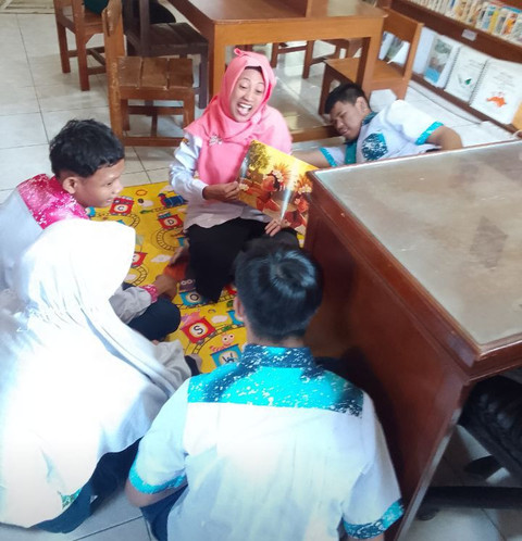 Bu Rachmalia Maya Sutikno, Kepala Perpustakaan SLB Negeri Semarang, (dua dari kiri), menghidupkan narasi dari buku cerita bergambar kepafa anak-anak tunagrahita kelas 7 di ruang kerjanya, Rabu (30/4/2025). (Foto: Mohamad Jokomono)