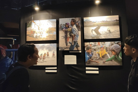 Pengunjung mengamati karya foto pada pameran foto 'Sing Penting Madhang' di Gallery Gelanggang Inovasi dan Kreativitas (GIK) Universitas Gadjah Mada (UGM), Kamis (1/5/2025) malam. Foto: Arfiansyah Panji Purnandaru/kumparan