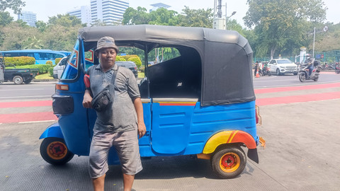 Sosok Tris Wanto (42), sopir bajaj yang selalu mangkal di depan jalur pejalan kaki Pintu Selatan Stasiun Gambir, Jakpus, bersama 3 sopir lainnya, Jumat (2/5/2025). Foto: Thomas Bosco/kumparan