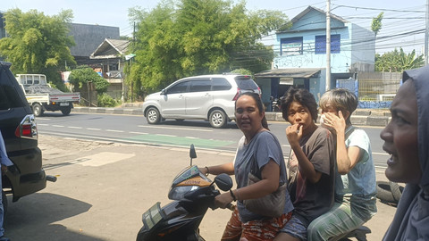 Leona (34), warga Bekasi Timur yang datang ke Ruko Worldcoin di Jalan Insiyur H Juanda, yang telah tutup membonceng anak dan ibunya, Senin (5/5/2025). Foto: Thomas Bosco/kumparan
