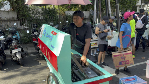 Aden (30), menjual jajanan jadul es goyang di kawasan CFD Sudirman-Thamrin, Jakarta Pusat pada Minggu (11/5/2025). Foto: Abid Raihan/kumparan
