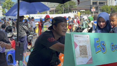 Aden (30), menjual jajanan jadul es goyang di kawasan CFD Sudirman-Thamrin, Jakarta Pusat pada Minggu (11/5/2025). Foto: Abid Raihan/kumparan