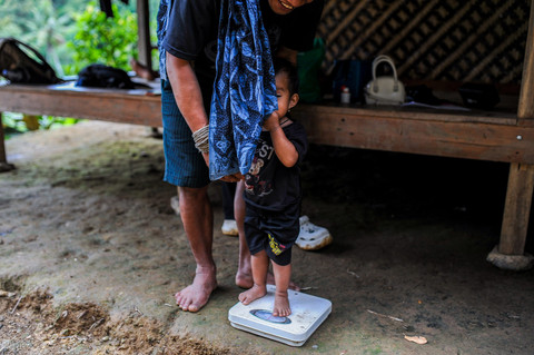 Bapak Suku Baduy menimbang berat badan anaknya sebelum pemberian vitamin A di Kampung Pamoean, Lebak, Banten. Foto: Muhammad Bagus Khoirunas/ANTARA FOTO