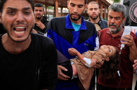 Seorang pria Palestina menggendong seorang anak yang terluka, setelah Rumah Sakit Eropa rusak sebagian akibat serangan udara Israel, menurut Kementerian Kesehatan Gaza, di Khan Younis, di Jalur Gaza selatan, 13 Mei 2025. Foto: REUTERS/Hatem Khaled