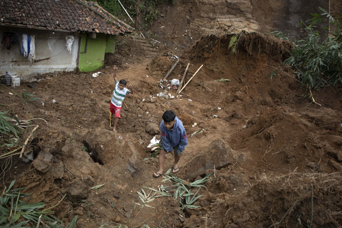 Dua orang anak berjalan di dekat material tanah longsor yang menimbun fasilitas umum dan kolam pemancingan di Lembang, Kabupaten Bandung Barat, Jawa Barat, Kamis (15/5/2025). Foto: Abdan Syakura/ANTARA FOTO