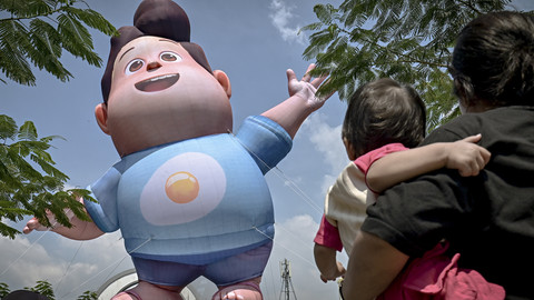 Seorang bapak menggendong anakanya melihat balon raksasa Don 'JUMBO' saat berwisata di Kota Tua, Jakarta, Minggu (18/5/2025). Foto: Jamal Ramadhan/kumparan