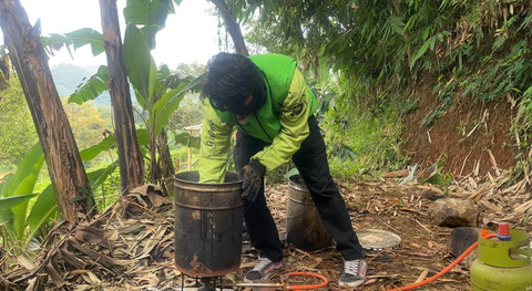 Pengemudi ojek online, Hasan Fiidel, menambal jalan rusak di Kabupaten Bandung. Foto: kumparan