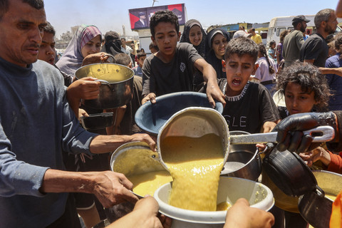 Warga Palestina mengantre untuk menerima makanan hangat di titik distribusi makanan di lingkungan Al-Rimal di Kota Gaza di Jalur Gaza bagian tengah, Rabu (21/5/2025). Foto: OMAR AL-QATTAA/AFP