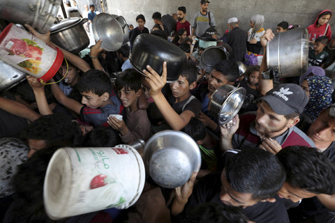 Warga Palestina menunggu untuk menerima makanan yang dimasak oleh dapur amal, di Kota Gaza, Rabu (21/5/2025). Foto: Mahmoud Issa/REUTERS