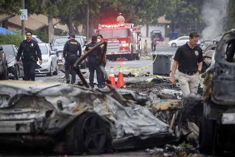 Petugas kepolisian memeriksa puing-puing kendaraan yang terbakar akibat kecelakaan pesawat kecil di San Diego, California, Amerika Serikat, Kamis (22/5/2025). Foto: Sandy Huffaker / AFP
