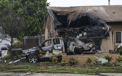 Suasana rumah dan kendaraan yang terbakar akibat kecelakaan pesawat kecil di San Diego, California, Amerika Serikat, Kamis (22/5/2025). Foto: Sandy Huffaker / AFP