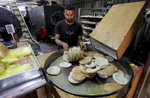 Pekerja menyelesaikan pembuatan roti di salah satu toko roti di Deir Al-Balah, di Jalur Gaza tengah, Kamis (22/5/2025). Foto: Ramadan Abed/REUTERS