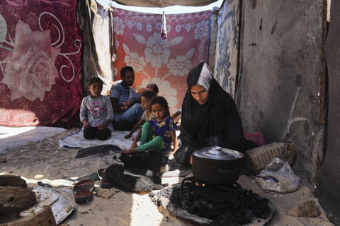 Keluarga Al-Arja menyantap sup miju-miju di dalam tenda mereka di kamp pengungsian warga Palestina di Muwasi, Khan Younis, Gaza, Rabu (21/5/2025). Foto: Abdel Kareem Hana/AP PHOTO