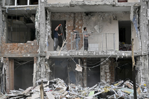 Penduduk setempat dari sebuah bangunan perumahan bertingkat membersihkan puing-puing dari sebuah flat yang rusak setelah serangan pesawat tak berawak di Kyiv, Minggu (25/5/2025). Foto: Sergei Supinsky/AFP