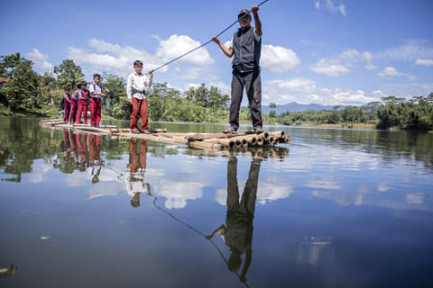 Sejumlah siswa SDN Panaruban menyeberangi sungai Cicadas menggunakan rakit di Desa Karanganyar, Cililin, Kabupaten Bandung Barat, Jawa Barat, Selasa (27/5/2025). Foto: Abdan Syakura/ANTARA FOTO