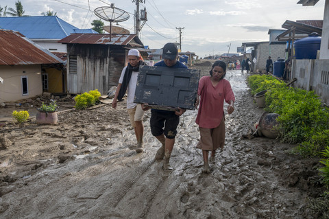 Warga korban banjir bandang membawa televisi melintasi jalan berlumpur di Desa Wombo, Kecamatan Tanantovea, Kabupaten Donggala, Sulawesi Tengah, Kamis (29/5/2025). Foto: Basri Marzuki/ANTARA FOTO