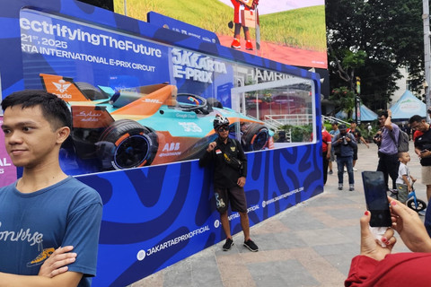 Sejumlah warga berfoto di depan mobil balap Formula E yang dipajang di sekitar kawasan Bundaran HI, Jakarta, Minggu (1/6/2025). Foto: Luthfi Humam/kumparan