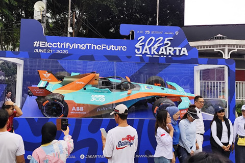Sejumlah warga berfoto di depan mobil balap Formula E yang dipajang di sekitar kawasan Bundaran HI, Jakarta, Minggu (1/6/2025). Foto: Luthfi Humam/kumparan