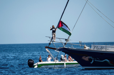 Aktivis iklim Greta Thunberg berdiri di dekat bendera Palestina setelah menaiki kapal Madleen dan sebelum berlayar menuju Gaza bersama dengan aktivis Koalisi Armada Kebebasan di Catania, Italia, Minggu, (1/6/2025). Foto: Salvatore Cavalli/AP PHOTO