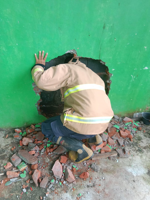 Petugas Damkar evakuasi seorang nenek bernama Rami yang terjepit di sela-sela tembok rumah warga di Dusun Prambon gang 01, Desa Klotok, Kecamatan Balongpanggang, Kabupaten Gresik. Foto: Damkar Kabupaten Gresik