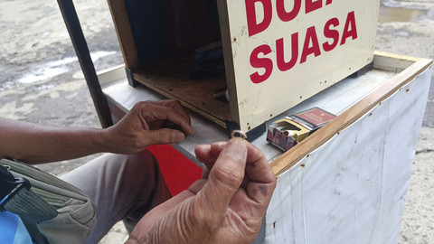 Ujang (53), jasa beli logam mulia dan dolar di pinggir jalan sekitar pertigaan Mal Cijantung, Jaktim, Selasa (3/6/2025).  Foto: Thomas Bosco/kumparan