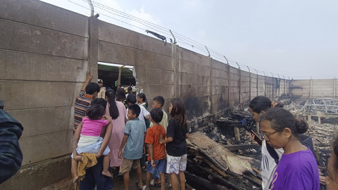 Tembok pembatas yang sebelumnya membatasi warga masuk ke lahan milik Duta Harapan Indah, kini bolong karena dijebol untuk menyelamatkan diri dari kebakaran, Sabtu (7/6/2025).  Foto: Thomas Bosco/kumparan