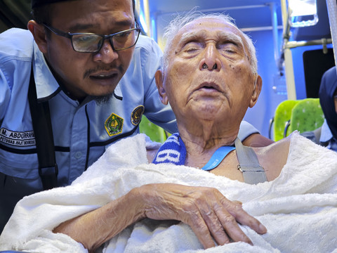 Petugas layanan lansia PPIH Arab Saudi Abdurrahman (kiri) membisikkan kalimat talbiyah di dekat telinga calon haji lansia Soemarno di atas bus khusus saat perjalanan menuju Masjidil Haram untuk menunaikan umrah wajib. Foto: Andika Wahyu/ANTARA FOTO