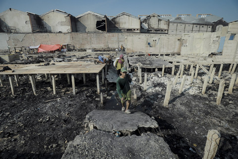 Seorang warga mengevakuasi barangnya yang selamat dalam kebakaran permukiman padat penduduk di Jalan Kapuk Raya, Kapuk Muara, Penjaringan, Jakarta, Minggu (8/6/2025). Foto: Jamal Ramadhan/kumparan