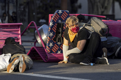 Para demonstran berlindung di balik barikade darurat ketika bentrokan dengan aparat keamanan saat melakukan aksi protes menentang razia imigrasi federal di pusat kota Los Angeles, California, Minggu (8/6/2025). Foto: ETIENNE LAURENT/AFP
