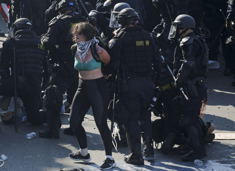 Petugas kepolisian menahan para demonstran dalam aksi protes menentang razia imigrasi federal, di pusat kota Los Angeles, California, AS, Minggu (8/6/2025). Foto: Mike Blake/REUTERS