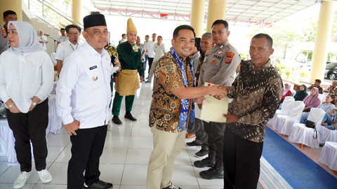 Ketua Komisi II DPR RI, Muhammad Rifqinizamy Karsayuda, didampingi Bupati Bolmong, menyerahkan sertifikat tanah milik masyarakat yang ikut program PTSL dari Kementerian ATR/BPN.