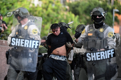 Polisi menangkap demonstran yang menolak kebijakan imigrasi dari Presiden Donald Trump di dekat Balai Kota Los Angeles, Amerika Serikat, Rabu (11/6/2025). Foto: Ronaldo Schemidt / AFP