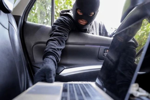 Seorang penjahat sedang mencuri laptop yang terletak di kursi belakang mobil. (Sumber: Shutterstock)