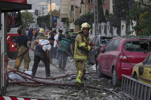 Petugas pemadam kebakaran dan warga membersihkan lokasi ledakan di sebuah kompleks perumahan setelah serangan Israel di Teheran, Jumat (13/6/2025). Foto: Vahid Salemi/AP Photo