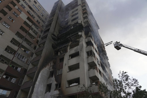 Seorang petugas pemadam kebakaran berdiri di atas derek di lokasi ledakan di sebuah kompleks perumahan setelah serangan Israel di Teheran, Jumat (13/6/2025). Foto: Vahid Salemi/AP Photo