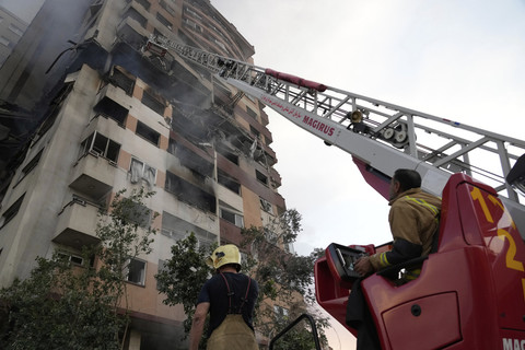 Petugas pemadam kebakaran bekerja di lokasi ledakan di sebuah kompleks perumahan di Teheran utara, Iran, Jumat (13/6/2025). Foto: Vahid Salemi/AP Photo