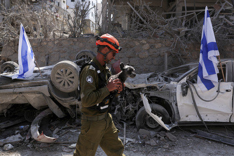 Petugas tanggap darurat melintas di dekat kendaraan yang hancur akibat serangan Iran di salah satu perumahan di Tel Aviv, Israel, Sabtu (14/6/2025). Foto: Ronen Zvulun/Reuters
