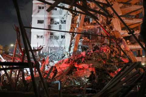 Petugas tanggap darurat meninjau kondisi bangunan yang hancur imbas serangan rudal Iran di kota Bat Yam, Israel, Minggu (15/6/2025). Foto: JACK GUEZ / AFP