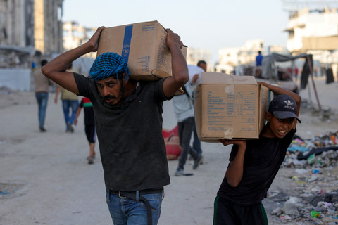 Warga Palestina yang mengungsi mengangkut paket bantuan kemanusiaan di sebelah barat Jabalia, Jalur Gaza utara, Senin (16/6/2025). Foto: Bashar Taleb / AFP