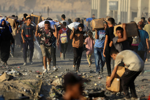Warga Palestina yang mengungsi mengangkut paket bantuan kemanusiaan di Beit Lahia, Jalur Gaza utara, Senin (16/6/2025). Foto: Dawoud Abu Alkas/REUTERS