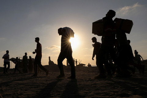 Warga Palestina yang mengungsi mengangkut paket bantuan kemanusiaan di Beit Lahia, Jalur Gaza utara, Senin (16/6/2025). Foto: Dawoud Abu Alkas/REUTERS