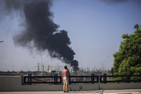 Seorang pria Israel melihat asap yang membumbung tinggi setelah serangan rudal dari Iran, di Herzliya, Israel, Selasa (17/6/2025). Foto: Itai Ron/REUTERS