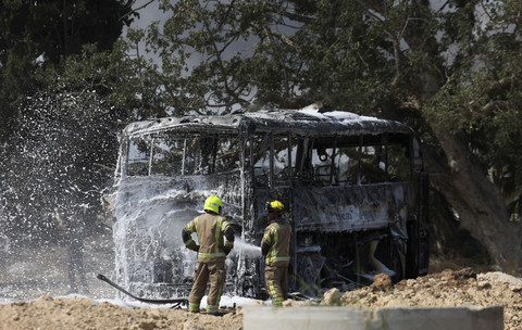 Petugas pemadam kebakaran berusaha memadamkan api di sebuah bus setelah serangan rudal dari Iran, di Herzliya, Israel, Selasa (17/6/2025). Foto: Ronen Zvulun/REUTERS