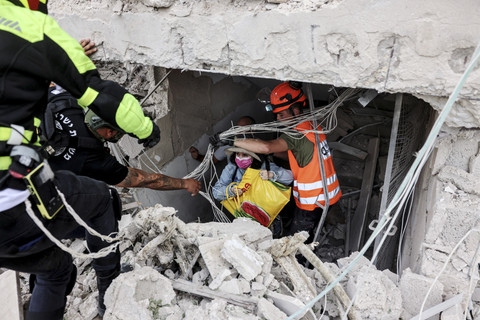 Petugas penyelamat mengevakuasi warga dari lokasi yang terkena dampak setelah serangan rudal dari Iran, di tengah konflik Iran-Israel di Tel Aviv, Israel, Minggu (22/6/2025). Foto: REUTERS/Tomer Appelbaum