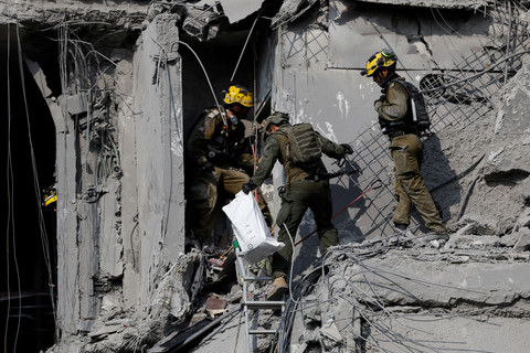 Petugas tanggap darurat melihat kondisi permukiman yang terkena dampak serangan rudal dari Iran di Be'er Sheva, Israel, Selasa (24/6/2025). Foto: Amir Cohen/REUTERS