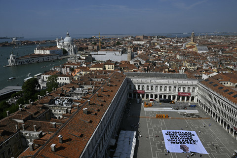 Sejumlah aktivis kelompok lingkungan internasional Greenpeace membentangkan spanduk raksasa yang menampilkan foto Jeff Bezos menjelang pernikahan Jeff Bezos di alun-alun St Mark, Venesia, Senin (23/6/2025). Foto: Stefano Rellandini/AFP